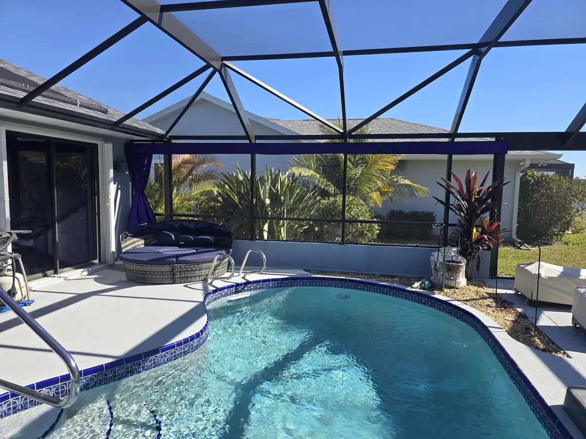 Purple shade sails over a pool and lanai in a white screen enclosure