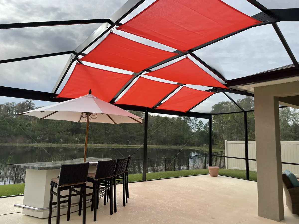 Red shade sails over a lakefront lanai bar area in a Florida screen enclosure