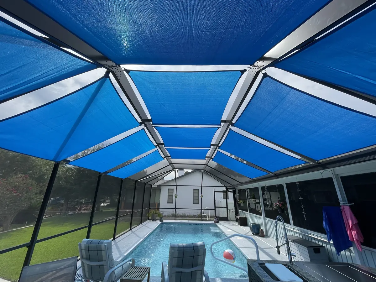 Royal blue shade sails covering a pool cage with a lap pool and screened lanai