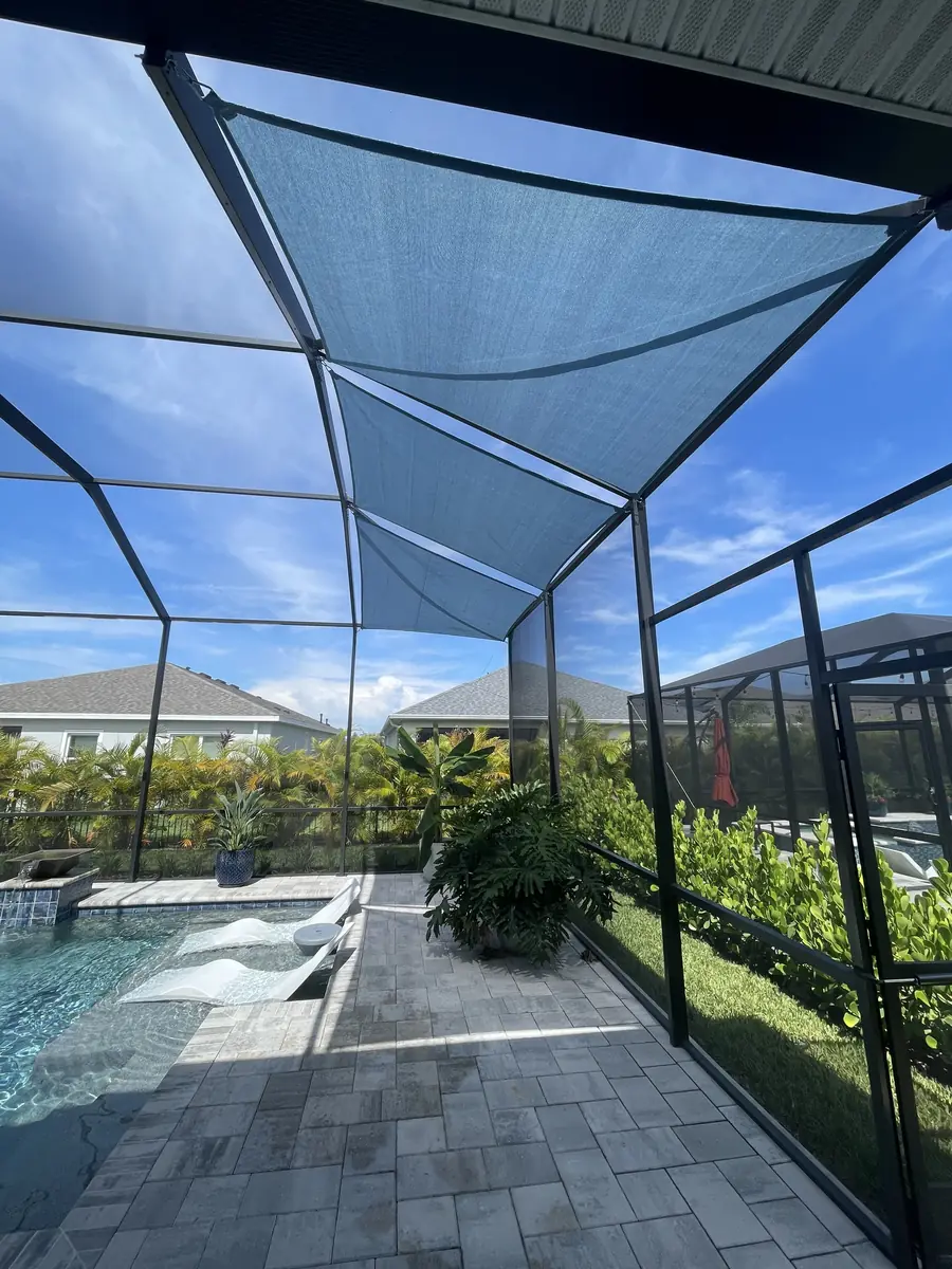 Sky blue shade sail over a rectangular pool in a bronze aluminum screen enclosure
