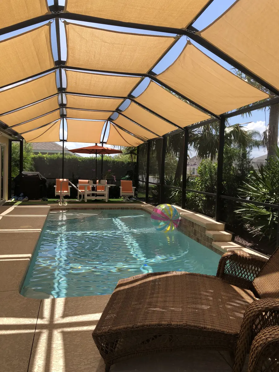Tan shade sails running the length of a lap pool enclosure in Florida