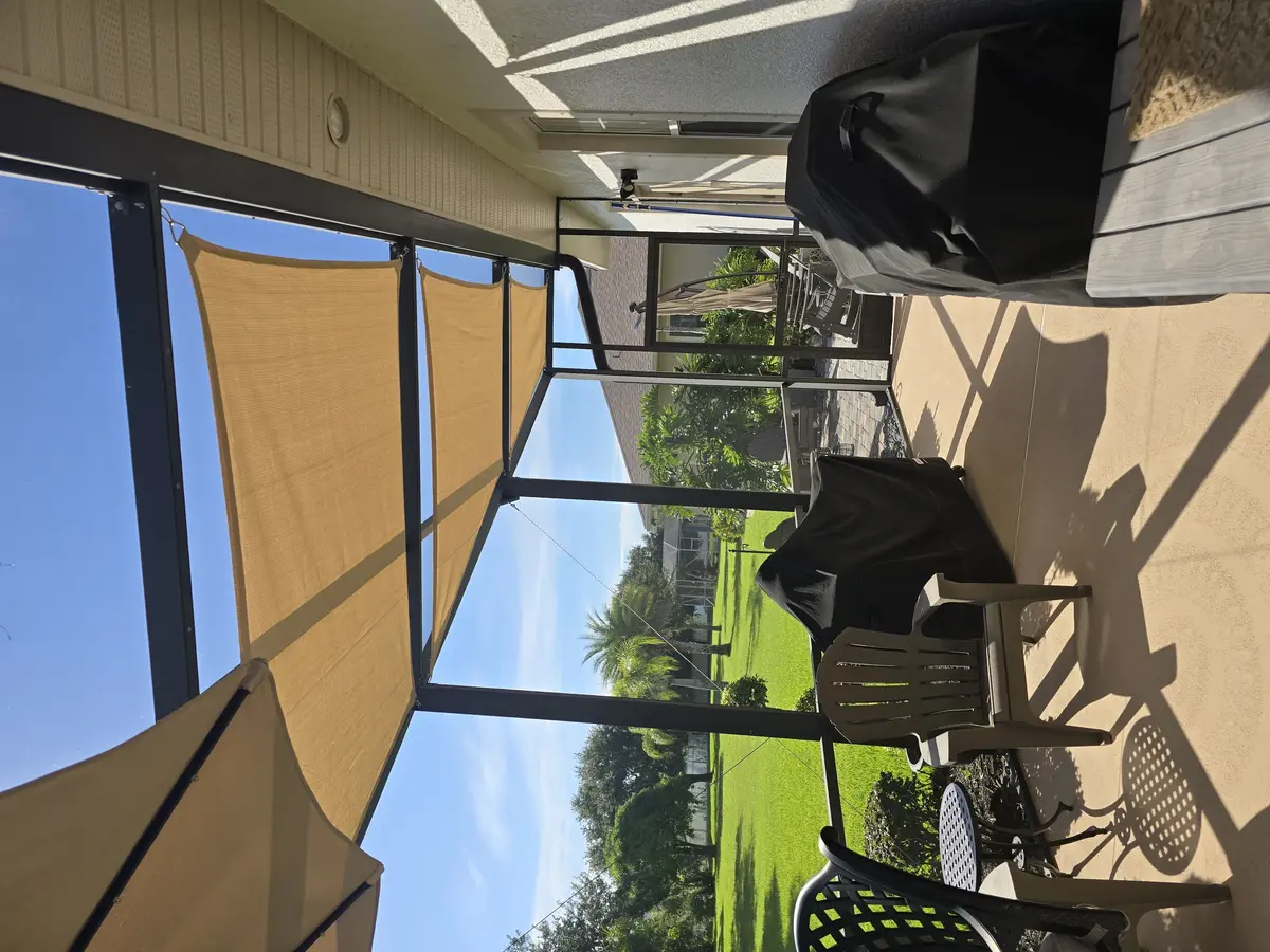 Tan SolaMesh shade sails providing UV protection in Florida pool enclosure