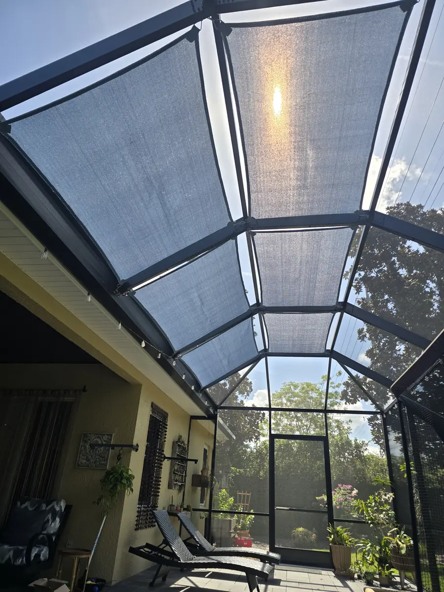 White shade sails under the roof of a bronze screen enclosure over a Florida lanai